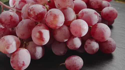 Ripe cluster of pink grapes slowly moves in the frame.
