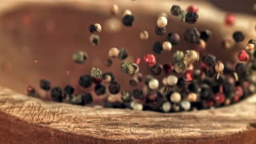 Multi Colored Peppercorns Fall Onto Wooden Surface