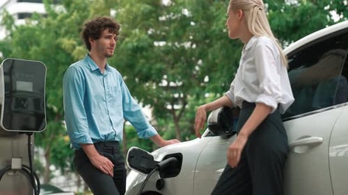 Progressive Businessman and Businesswoman Use Charging Station for EV Car