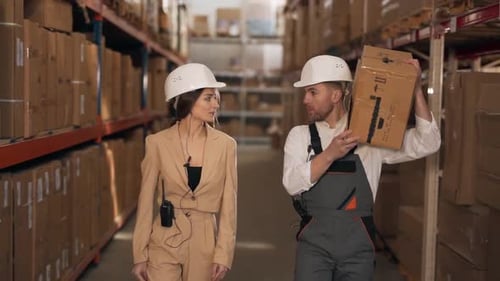Warehouse workers go with a cardboard box and talk