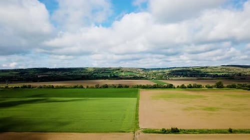 Aerial landscape ascending shot of cloudy bright and shady view of agricultural areas hills summer z