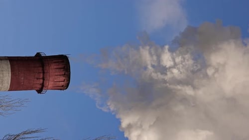Weißer Rauch steigt aus den Rohren einer Industrieanlage auf, Schadstoffemissionen aus Fabrikrauch