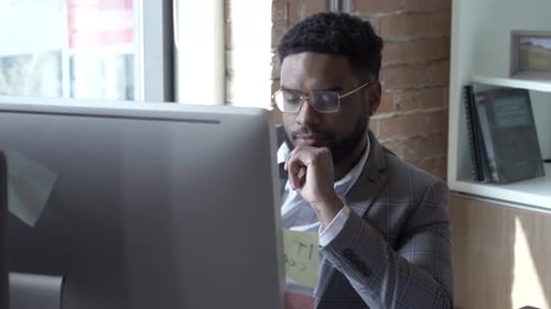 Focused young businessman working at computer in bright modern office