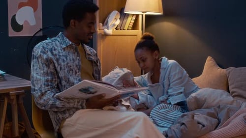 Man Reading Bedtime Story to Girl Indoors at Night