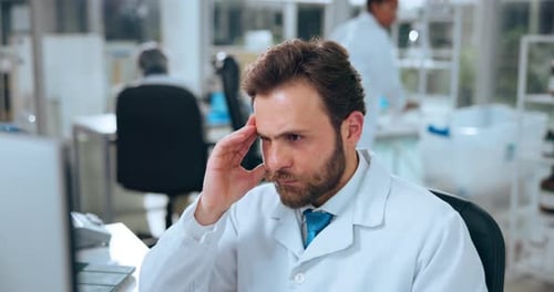 Thoughtful Man in Lab Coat Working at Computer