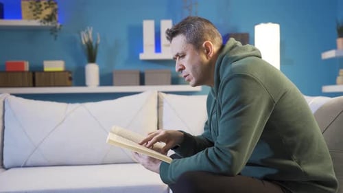 Man Reading Book on Couch Indoors