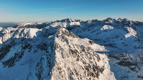 Breathtaking aerial view of snow-covered Alps under clear blue skies