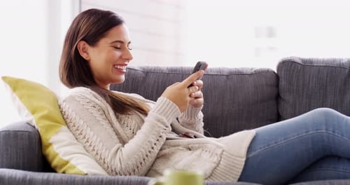 Woman, laughing and relax with cellphone on sofa, reading funny social network post