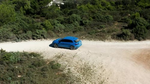 Blue Audi A3 Driving On Dirt Road At Cape Kamenjak Near Pula In Croatia During Summer. - Aerial Trac