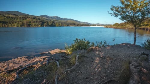 Calm lake scene surrounded by mountains and trees on a clear sunny day