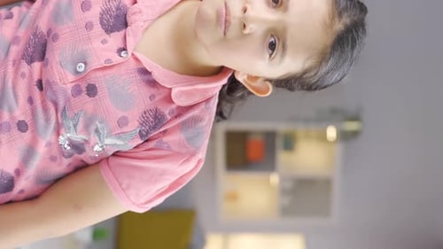 Vertical video of Girl child looking at camera with curious expression.
