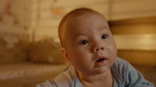 Small baby showing emotions on his face while lying on stomach.