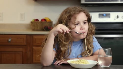 Girl Eats Spaghetti at Kitchen Table for Lunch