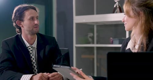 Männliche Führungskraft erklärt Geschäftsbericht einer Kollegin während einer Bürobesprechung und Präsentation