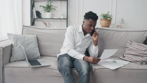 Young Adult Working From Home on Phone and Laptop