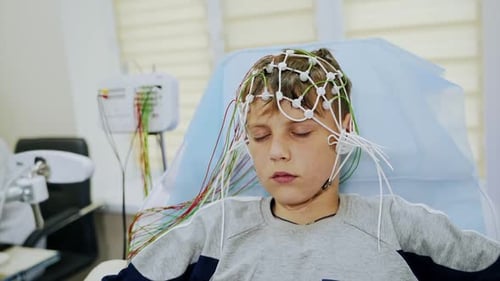 Der Teenager sitzt mit geschlossenen Augen und wird einem EEG-Test unterzogen.