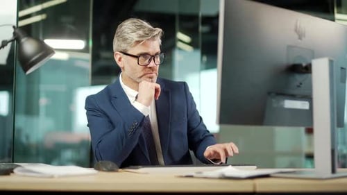 Portrait thoughtful male businessman working on pc computer at a modern office desk. Confident Focus