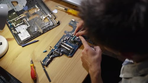 Man at Desk Applies Fresh Thermal Grease to Laptop Processor From Syringe