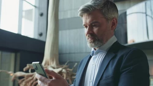 Bearded Man in Suit Using Smartphone Indoors