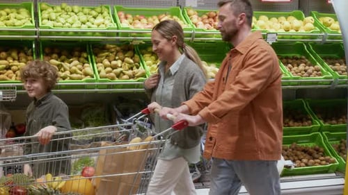 Parents and Son Happily Shopping Together in Supermarket, Father Pushing Cart