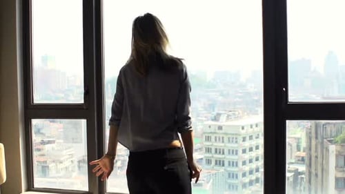 Woman dances joyfully in apartment overlooking city