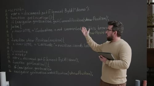Geeky Male IT Teacher Explaining Coding Variables to Class on Blackboard