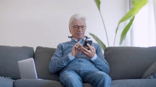 Senior Man Using Smartphone on Comfortable Couch