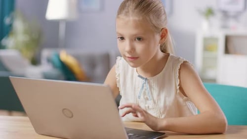 Girl using laptop computer at wooden desk