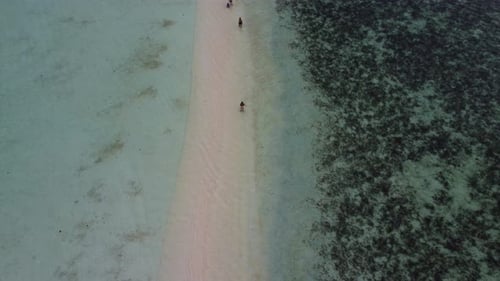 Tilt shot revealing a beautiful sand bar with people walking