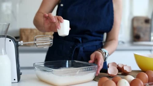 Woman Baking in Kitchen Adding White Powder to Bowl