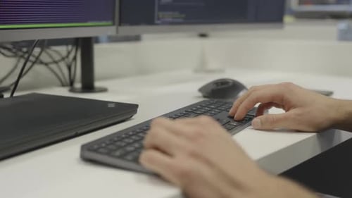 A man is typing on a computer keyboard, close up, side view
