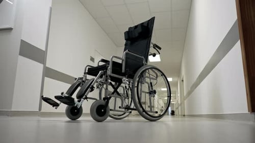 in a Modern Clinic in White Corridor There is a New Black Chair for the Disabled Assistance in