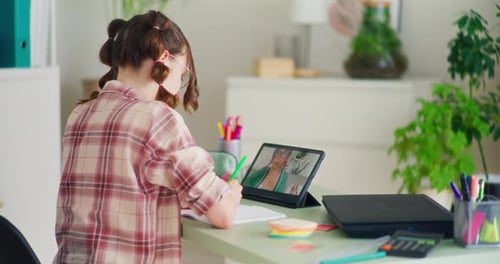 Teenager Video Calling and Writing at Desk