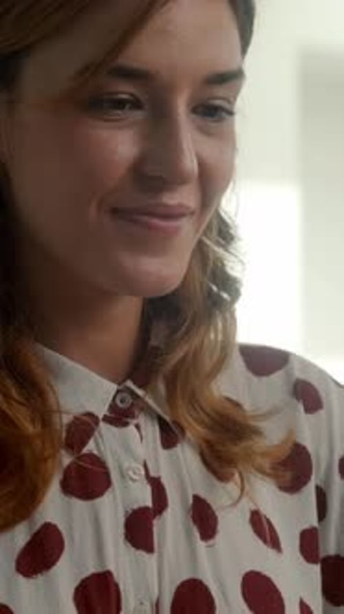 Jeune femme souriante et regardant vers le bas avec une lumière naturelle douce dans un environnement intérieur confortable