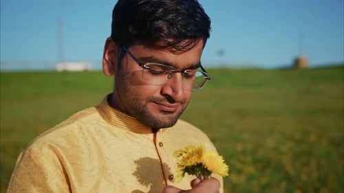 Young Indian Man Smelling Dandelions in a Field