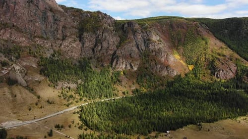 The Landscape From Above Reveals Forested Cliffs with Patches of Autumnal Colors a Winding Road