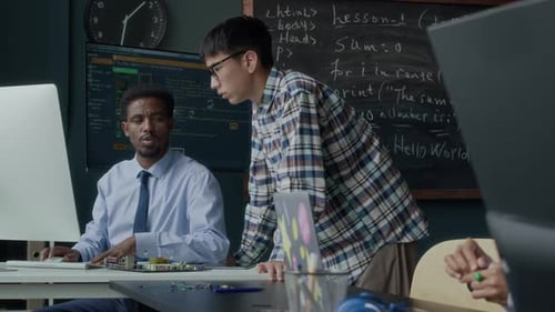 Asiatischer Student spricht während des Codierungs- und Robotikunterrichts mit dem Lehrer
