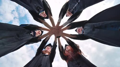 Graduates in Black School Uniforms Join Hands The Concept of Team and Strong Friendship
