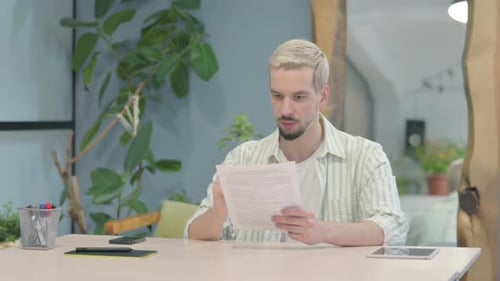 Modern Young Man Reading Documents in Office, Paperwork