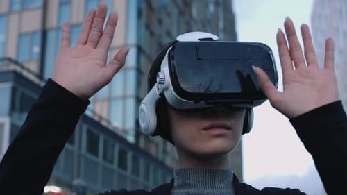 Woman Wearing VR Headset With Hands Up Outdoors