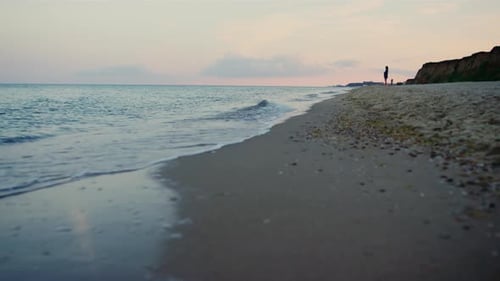 Woman silhouette walking sandy sea beach at pink sunset evening hills