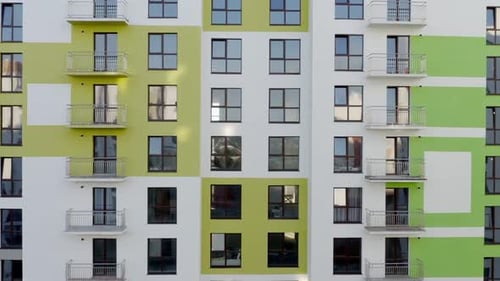 Slow Panning Shot Rising Up the Colorful Green and White Facade of a Highrise Building in an Urban