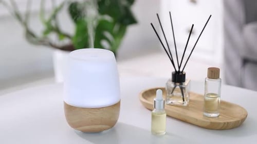 Aromathérapie. Lampe aromatique moderne, diffuseur à roseaux et bouteilles d'huiles essentielles sur une table lumineuse à l'intérieur