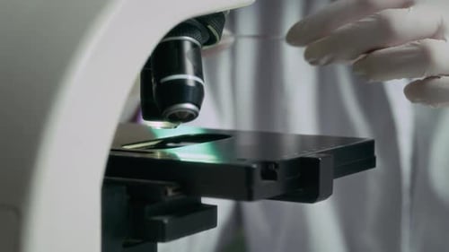 Scientist Examining Sample Under Microscope in Lab