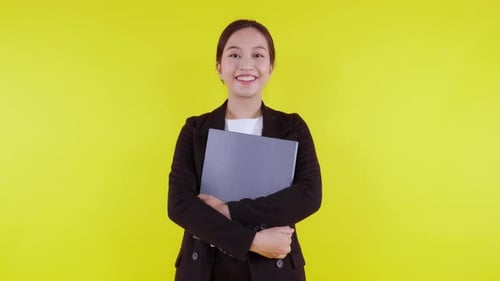 Portrait young asian businesswoman hold folder document smile on yellow background.