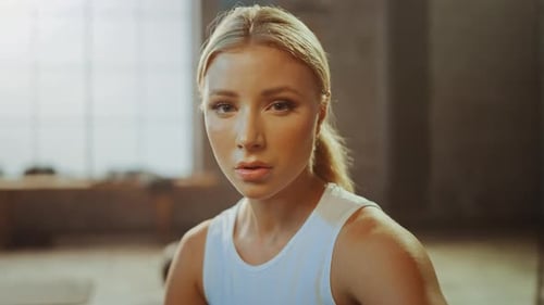Portrait of a Beautiful Strong Fit Blond Sitting in a Loft Industrial Gym with Motivational Posters