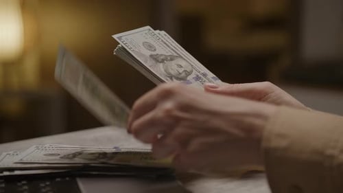 Hands Counting Hundred Dollar Bills at Table