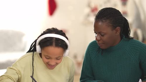 Woman Helping Girl with Homework at Table Indoors
