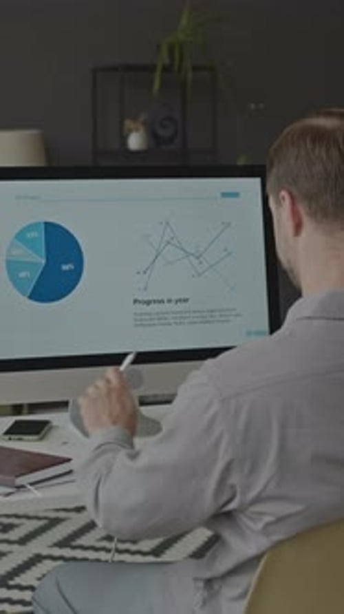Man Analyzing Business Diagram on Computer Monitor in Office