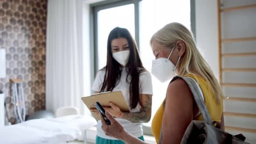 Healthcare Worker Shows Senior Woman Phone in Clinic